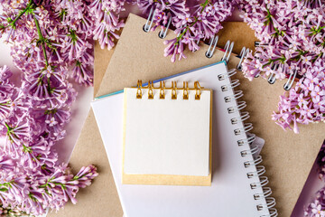 A beautiful floral composition and an empty paper notepad for text. Floral spring background with lilac. Copy space