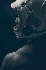 Black and white photo of a dark-skinned young guy. Standing in an astronaut's helmet and looking away