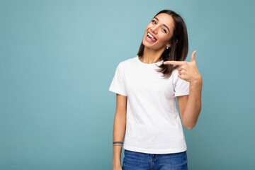 Portrait of beautiful fascinating emotional positive joyful happpy female promoter pointing to the side at copy space for advertising wearing hipster outfit isolated over background wall with empty