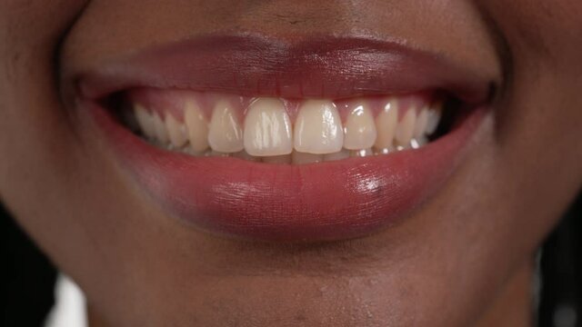 Close up of an African woman's mouth smiling with her teeth and then opening her mouth widely.