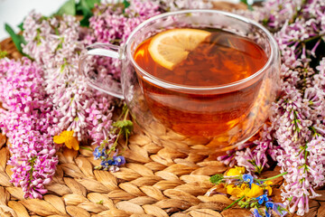 A mug of tea with lemon and lilac. Cozy romantic floral background with copy space. Flat lay.