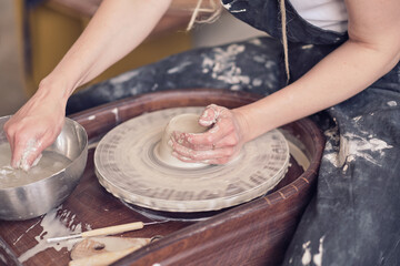 Close up female hands make dishes from clay. woman hands working on potters wheel. The master potter works in a workshop