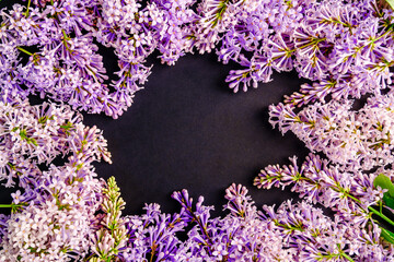 Fototapeta na wymiar Frame of lilac flowers, branches with space for text on black background. Flat lay, copy space