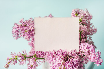 A beautiful floral composition and an empty paper notepad for text. Floral spring background with lilac. Copy space