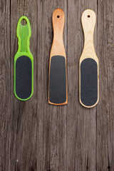 Wooden pedicure graters and a plastic foot file on wooden boards.