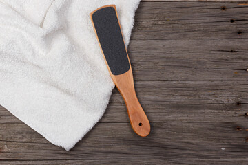 Pedicure grater with a towel on a wooden background. Top view