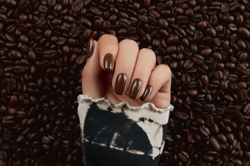 Beautiful groomed womans hand with brown nail design