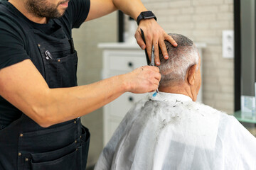 Obraz na płótnie Canvas Barber takes an senior customer's hair to cut with scissors. Close Up