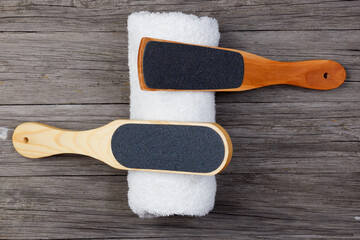 Pedicure grater with a towel on a wooden background. Top view
