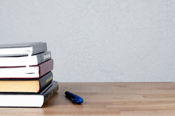 A stack of books on the table. A pen. Desk. Workplace.