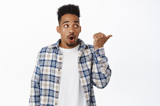 Image of surprised african american man gasp in awe, say wow, looking and pointing right at sale banner, showing discounts and stare astonished, white background