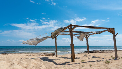 Wooden abandoned holiday pergola on a windy day at the beach.