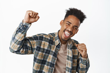 Portrait of happy african american guy chanting, raising fist up and screaming with rejoice,...