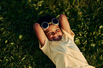 Lying down on the grass. African american kid have fun in the field at summer daytime