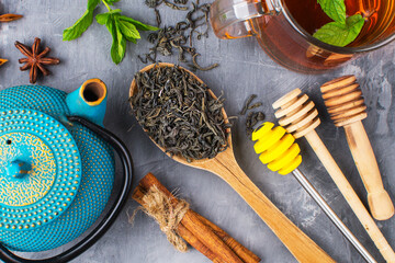 tea on a wooden spoon with a teapot and spices