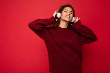 Photo of beautiful happy smiling young brunette curly woman wearing dark red sweater isolated over...