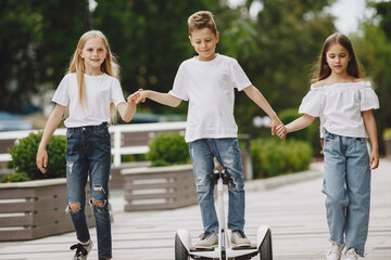 Children learn to ride hoverboard in a park on sunny summer day