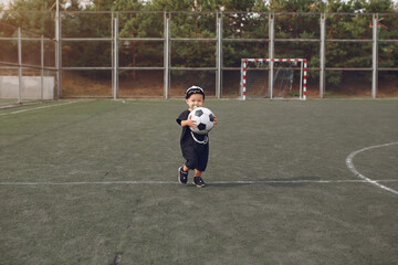 Little boy playing a football in a sports ground