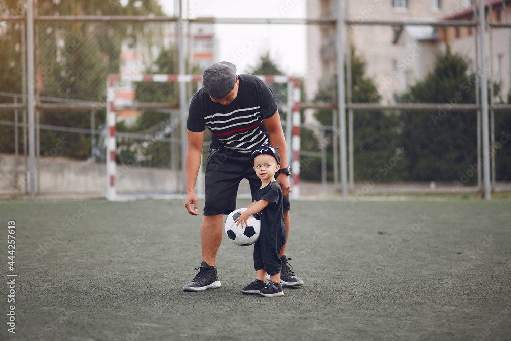 Wall mural Father with little son playing a football