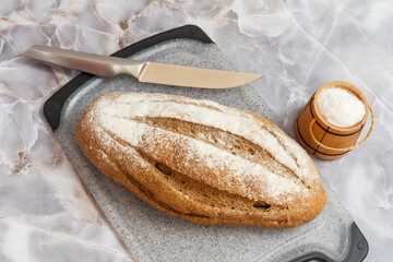 Loaf of bread on cutting board and knife on gray background