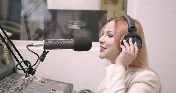 Happy young female radio host broadcasting in studio