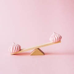 Creative food concept with a light wooden seesaw with pink cookies on it. Sweet  and summer layout...