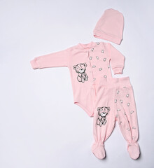 Children's things in pink color - a hat, a vest and romper - a set of things from one set with a cute children's print.