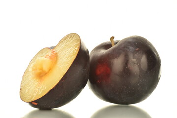 One whole and one half of sweet tasty dark purple plum, close-up, isolated on white.