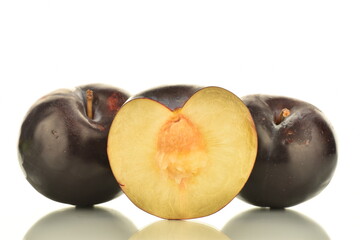 Two whole and one half sweet tasty dark purple plums, close-up, isolated on white.