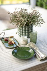 Table in the garden is covered with a tablecloth and decorated with flowers and candles with food for two persons. Summer dinner outdoor. 