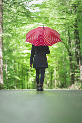 Frau mit rotem Regenschirm bei Spaziergang