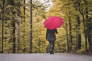 Frau mit rotem Regenschirm im Herbstwald