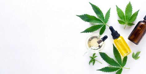Cannabis oil in bottle hemp oil and cannabis leaves at white background. Top view, copy space....