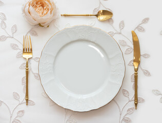 Wedding table arranged with golden cutlery and white charger plate. Mockup for menu, invitation card, festive concept in vintage style - Powered by Adobe