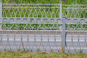 Metal fence of the roadway of the street on a summer day