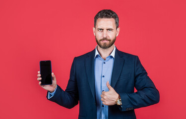 mature bearded businessman in suit presenting product. confident guy hold smartphone.