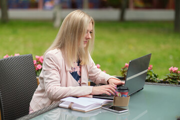 Beautiful woman working with laptop, on the street of old city on summer day, waist up