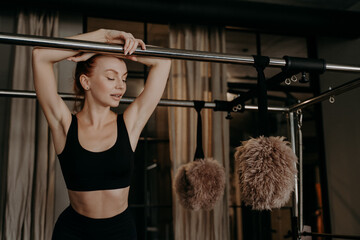 Beautiful redhead fitness woman relaxing on pilates cadillac reformer