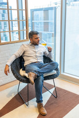 Handsome man tasting a glass of wine sitting in his living room