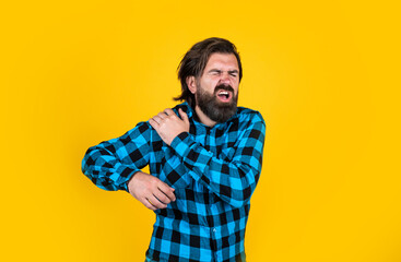 brutal bearded hipster feel pain. mature guy with moustache on face. expressing human emotions. suffering man in checkered shirt. man has ache in shoulder on yellow background