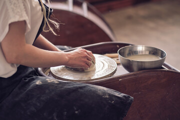 Close up female hands make dishes from clay. woman hands working on potters wheel. The master potter works in a workshop