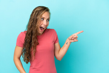 Young caucasian woman isolated on blue background pointing finger to the side and presenting a product