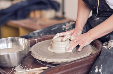 Close up female hands make dishes from clay. woman hands working on potters wheel. The master...