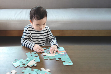 Asian little boy playing with puzzle pieces, infant early childhood education, child development concept.