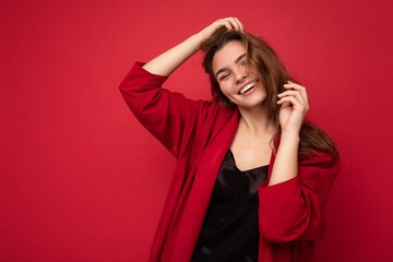 Portrait of young attractive caucasian hipster woman in trendy casual clothes. Sexy carefree female person posing isolated near red wall in studio. Empty space