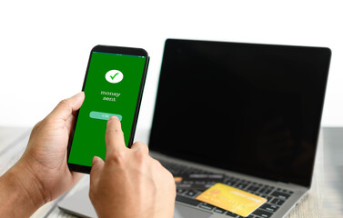 A man's hand holds a smartphone on screen with the message money sent and touching a button. Concept of financial transactions with mobile devices. money, transfer, phone, copy space. White backgroun