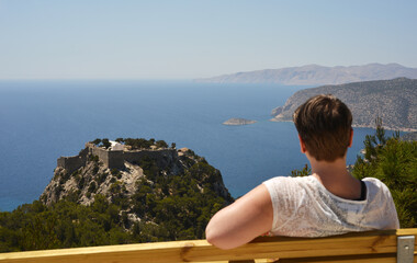 A woman looks to the ancient castle Monolithos in the south western part of Rhodes, Greece