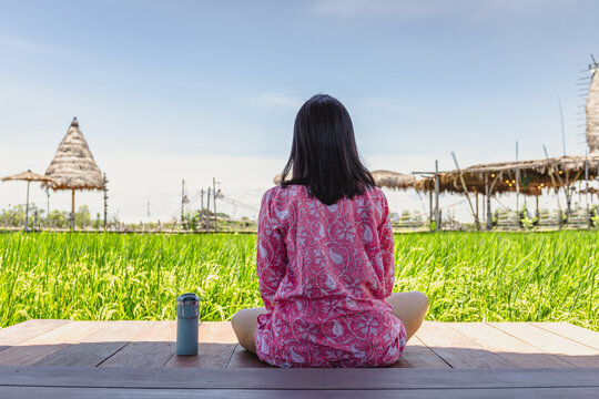 Woman sitting on wooden floor with thermos bottle look at beautiful landscape.