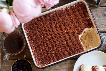 Homemade tiramisu. Peonies, coffee, blueberries. Wooden background. Top view.