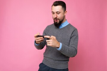 Shot of happy handsome young brunette unshaven man with beard wearing everyday grey sweater and...